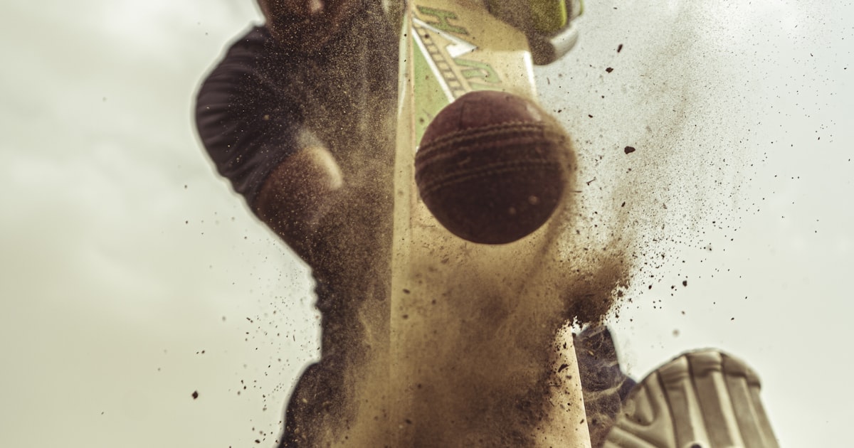 A cricket batsman at the crease during a T20 match with the wicketkeeper behind the stumps.